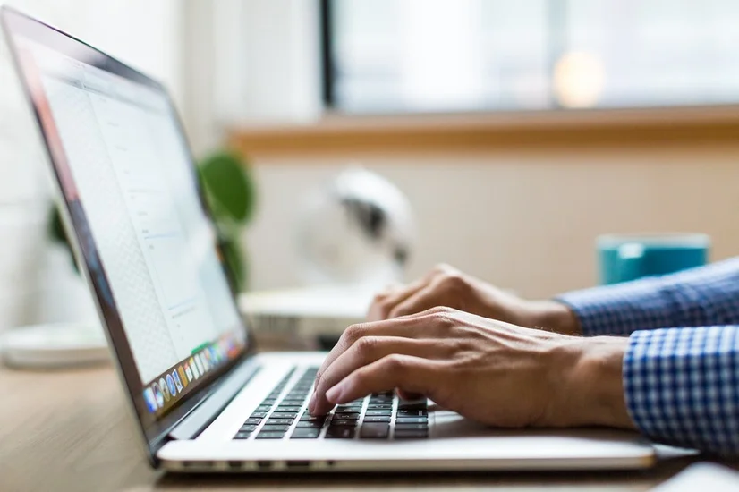 A close up of a man typing on a laptop.