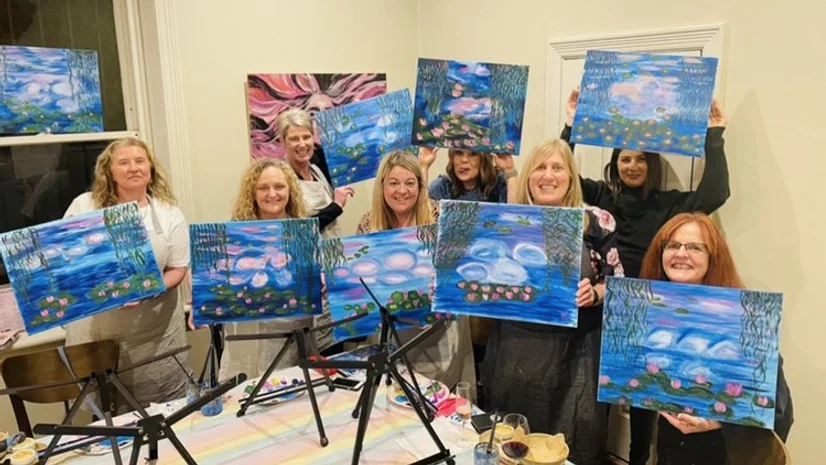 ladies smiling holding up artworks after class