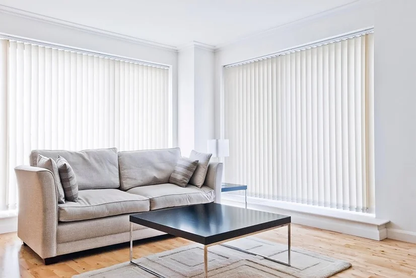White vertical blinds covering large windows in a lounge room.