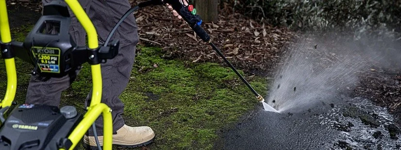 man removing weeds from concrete using pressure washer