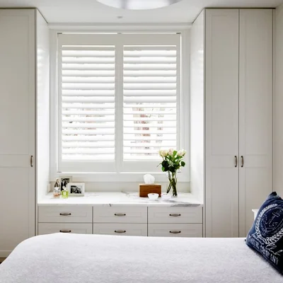 White plantation blinds in a light-filled bedroom.