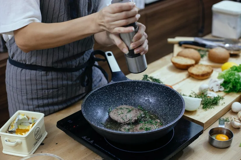 Woman using a portable induction stove to cook meat