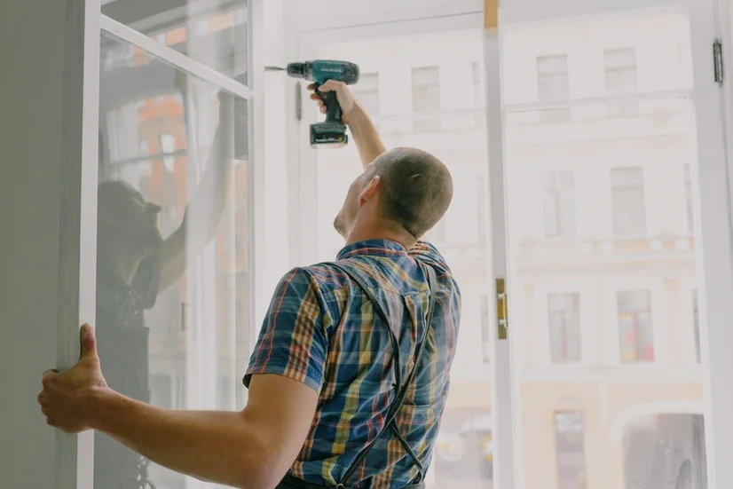 Handyman drilling into a window pane