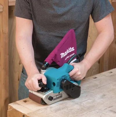 A man using a belt sander on a piece of wood