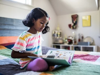 little girl reading on bed