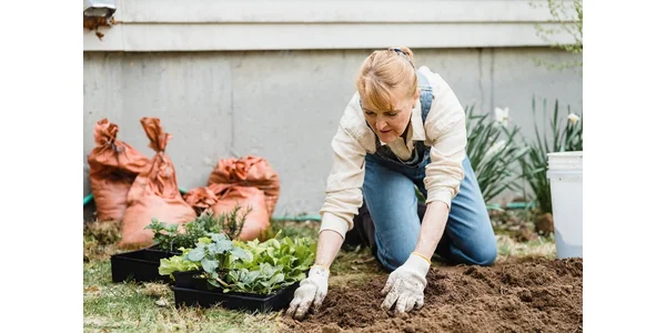 A woman wearing gloves and gardening in her yard