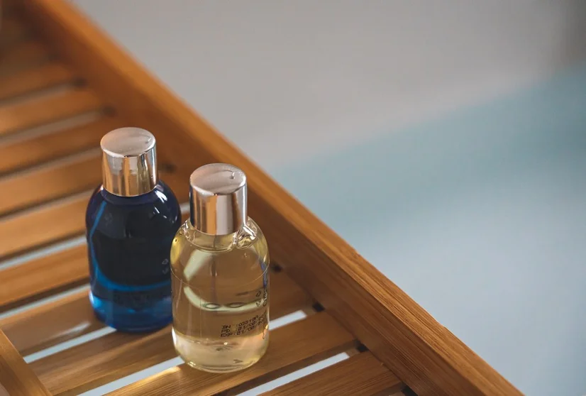 Two small perfume bottles sitting side by side on a wooden rack
