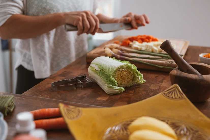 A person chopping up fresh vegetables in their kitchen.
