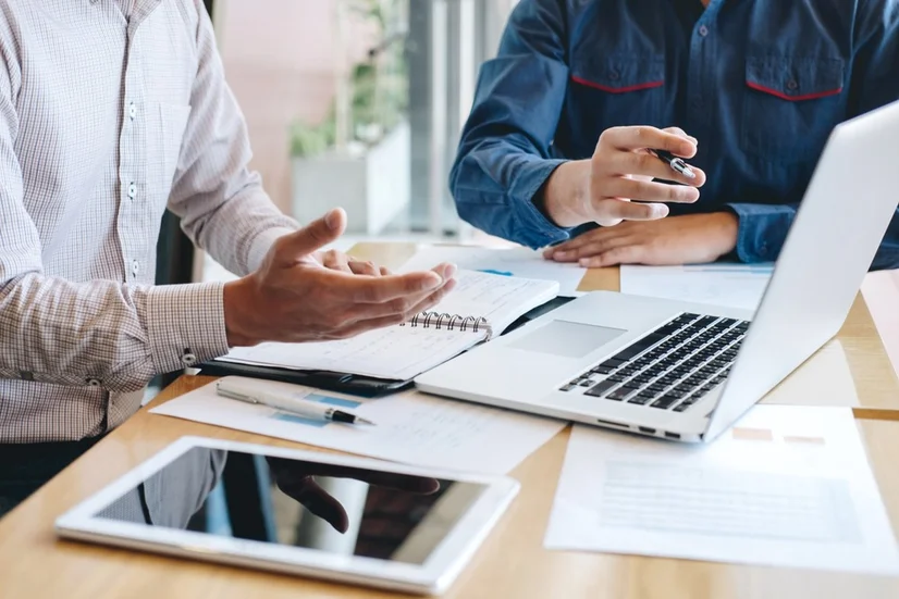 Two people at a desk looking at paperwork.