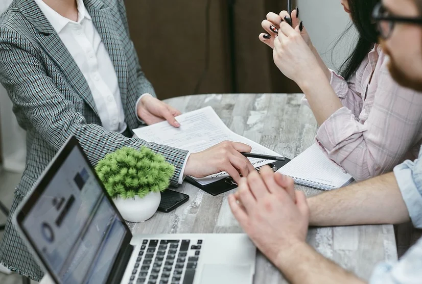 Three people sitting around a table and talking business.