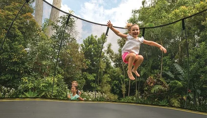 boy jumping on trampoline in backyard