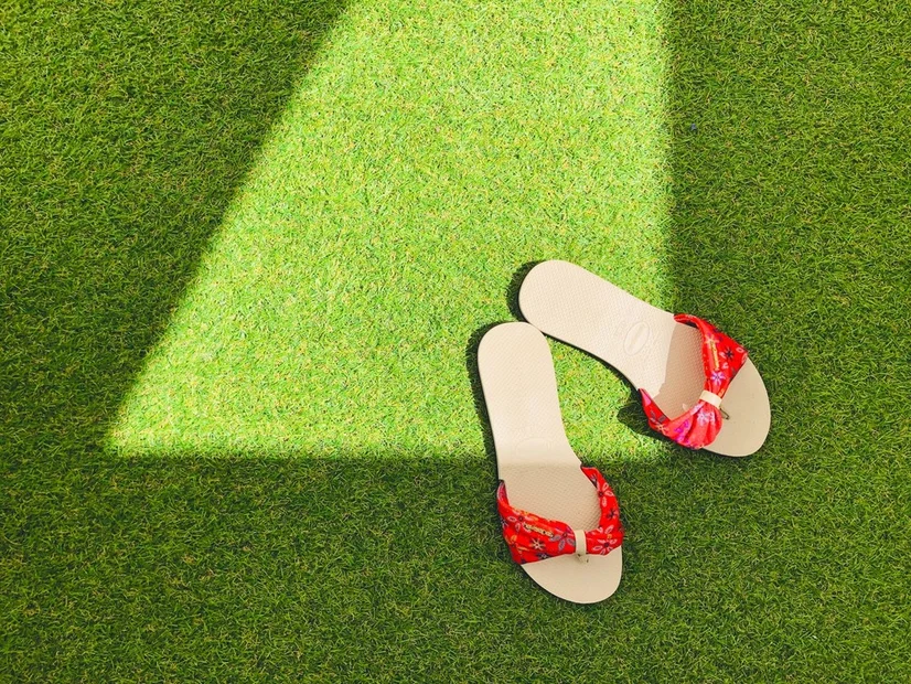 A pair of sandals sitting on an artificial lawn.