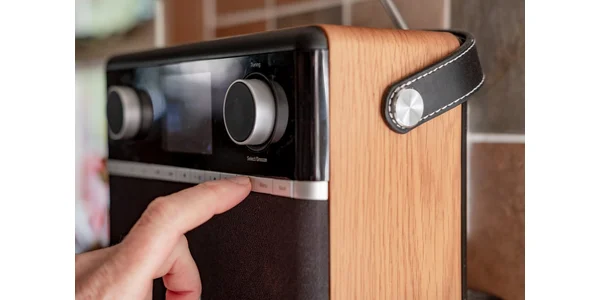 A close up of a man pressing a button on a desktop digital radio.