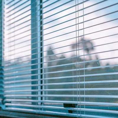 A close up of white Venetian blinds.