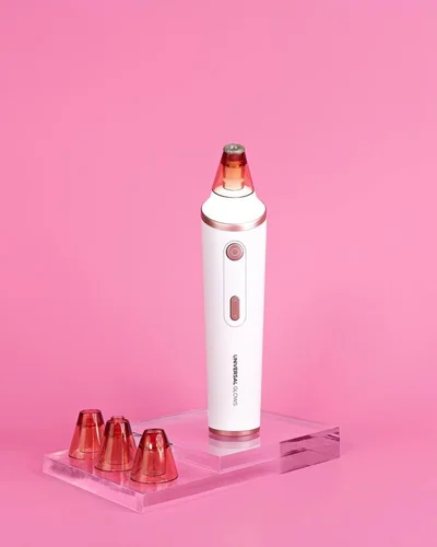 The Universal Glows Dermabrasion Kit with 3 different suction heads next to it, against a pink background.