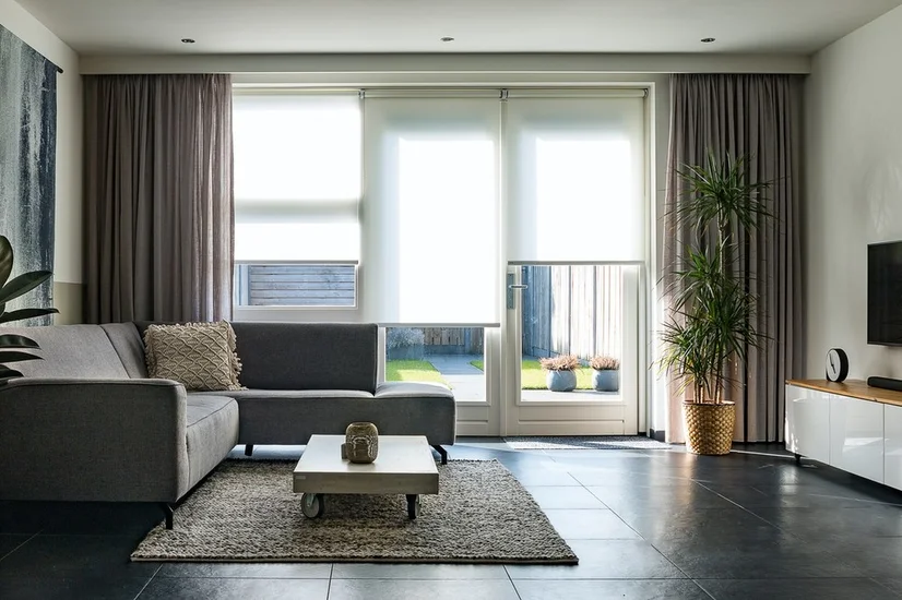 White roller blinds covering sliding doors in a lounge room.
