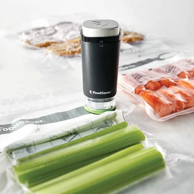 A handheld sealer being held against a sealer bag containing celery sticks