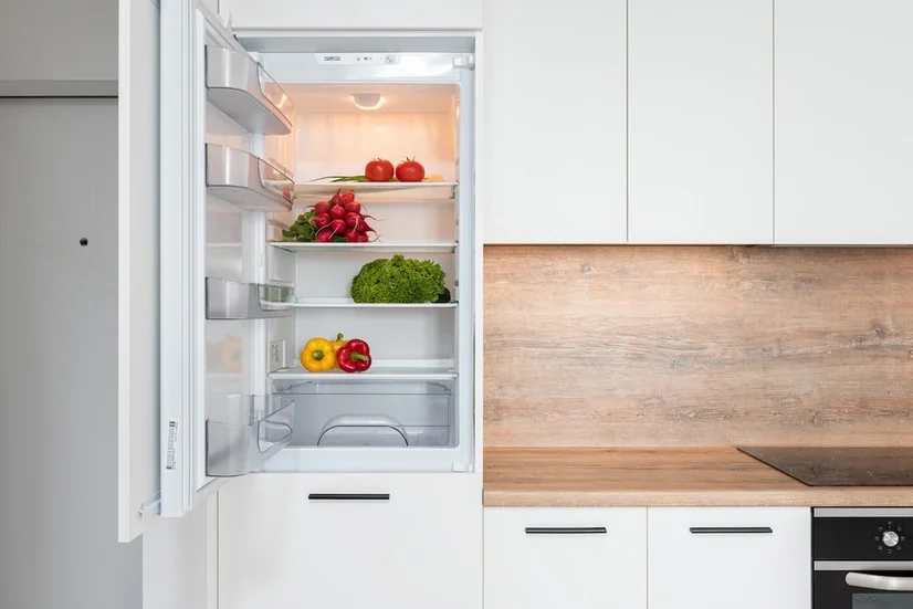 A french door fridge surrounded by wooden cabinetry.