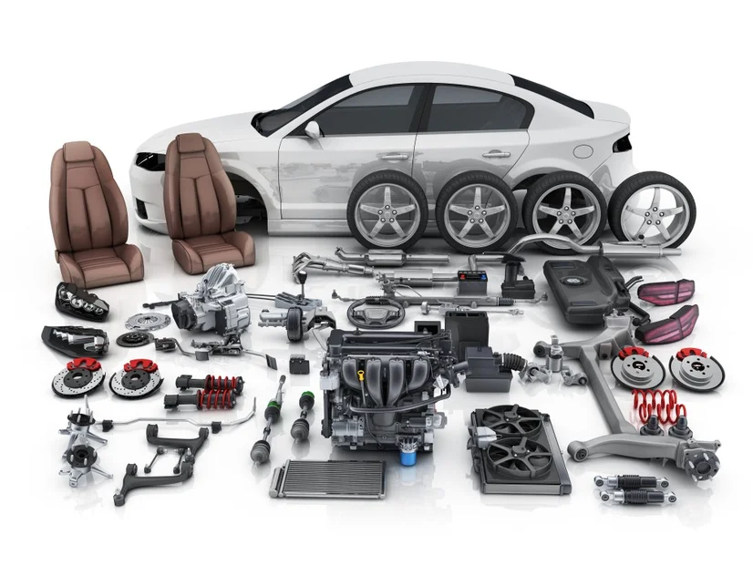 Various parts of a car, disassembled and laid out in front of a car body.