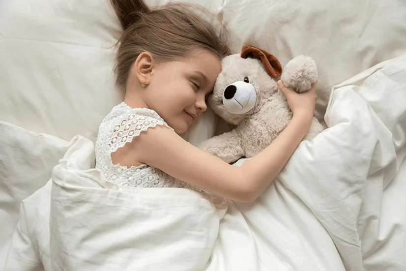 Little girl sleeping under a quilt