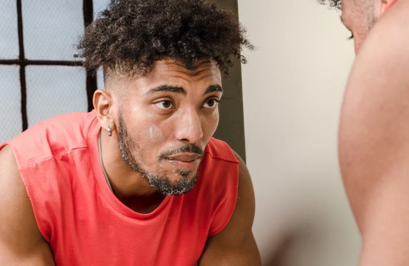 man using face wash in mirror