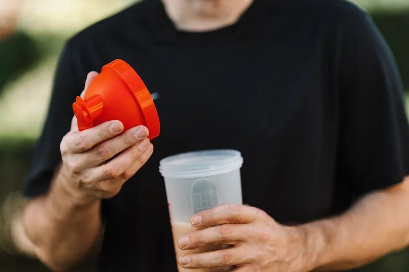 A man opening his protein shake bottle to drink his protein shake.