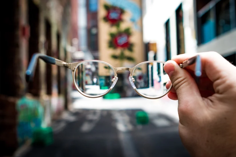 Man holding glasses on a blurry street