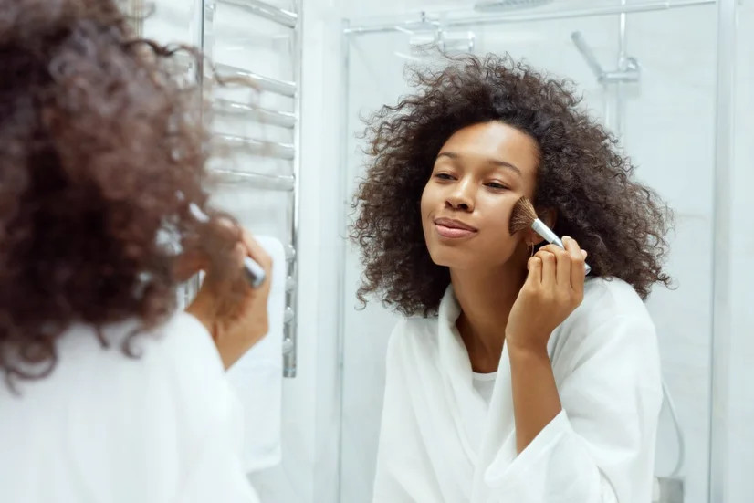 A woman applying blush to her cheekbones