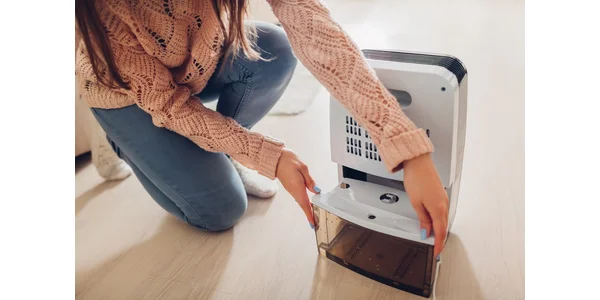 woman replacing water tank inside dehumidifier