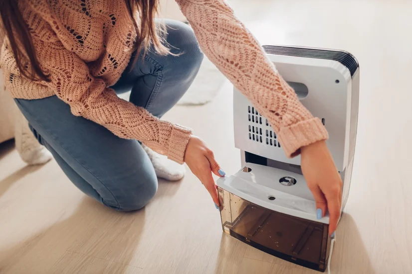 woman replacing water tank inside dehumidifier