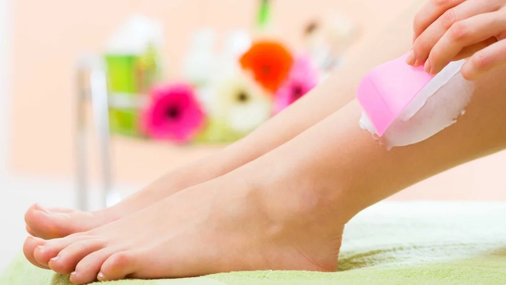 Woman at home removing depilatory cream with provided spatula