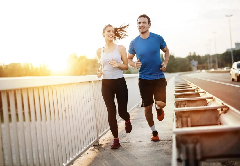 A woman and man happily jogging outdoors together.