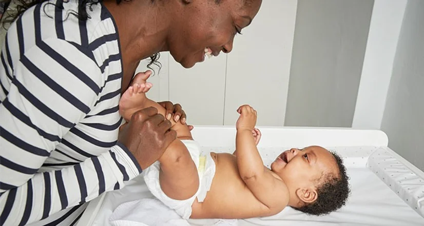 Happy baby getting a nappy change from mum