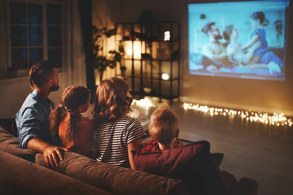Family watching TV enjoying a projector home set-up